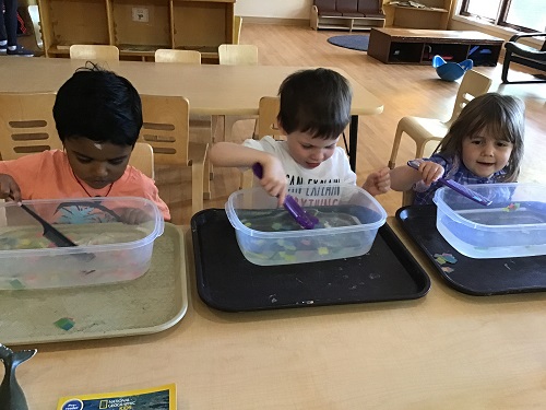 children playing with shart and whale toys in buckets of water