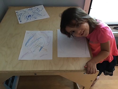 girl posing beside her drawings