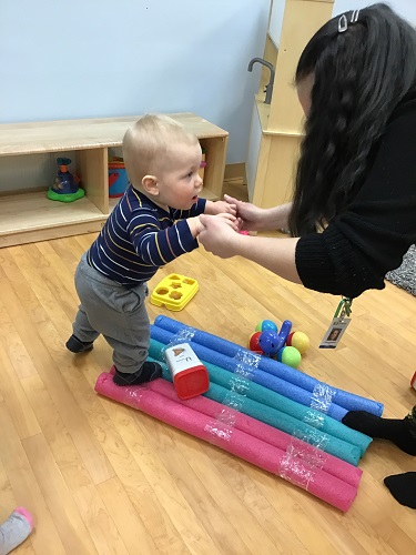 infant stepping on pool noodles