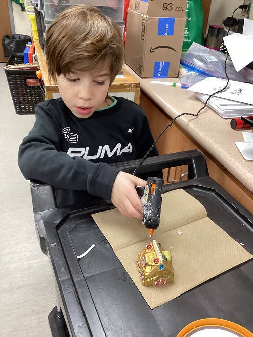 child adding gems to their gingerbread house