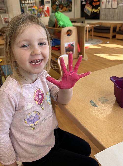 child holding up their painted pink hand