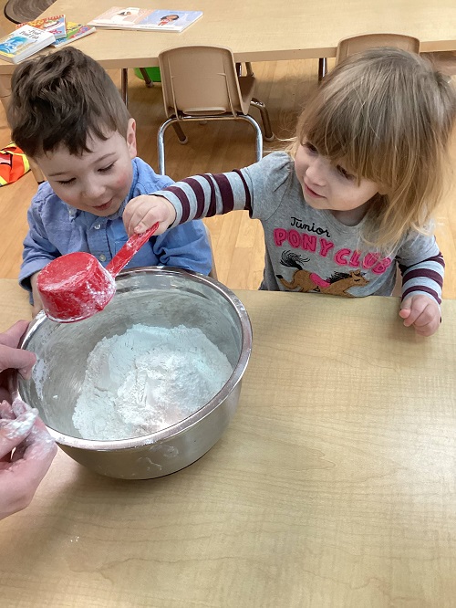 child dumping in ingredients into a bowl