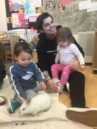 children sitting with their educator with a rabbit on the floor