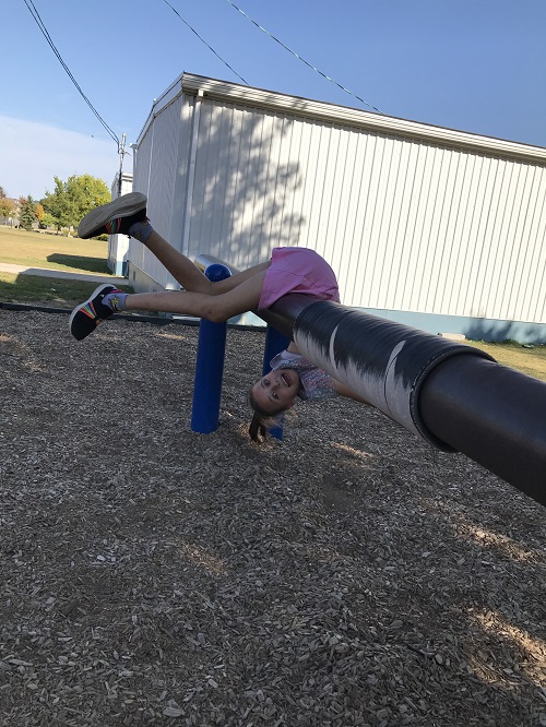 Child upsidedown on a balance beam. 