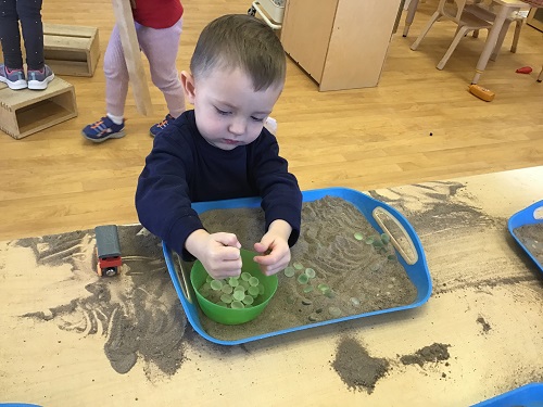 CHild exploring beads and sand.
