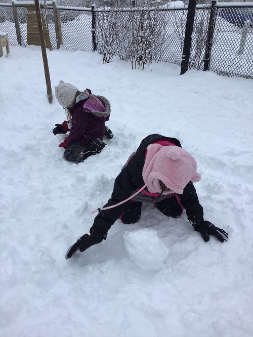 Child rolling a snowball.