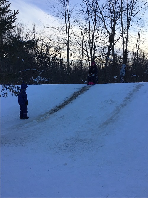 Children sledding on the snow hill.