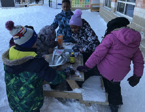 Children working together to make ice cream outside.