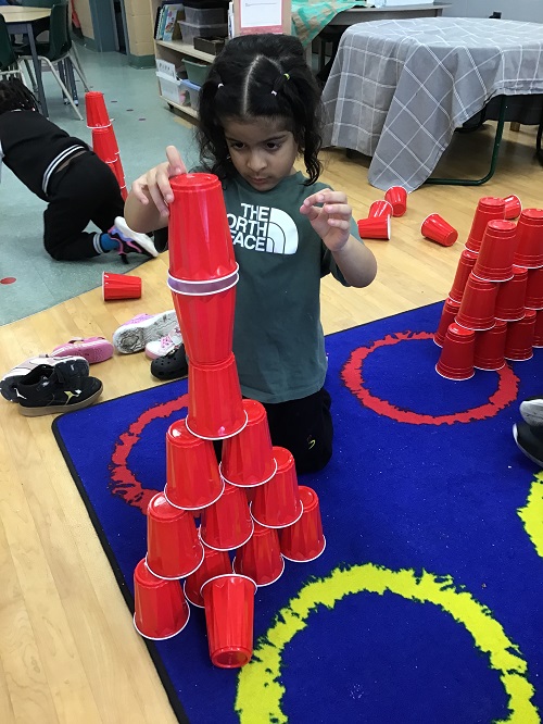 Child testing out new building way with solo cups.