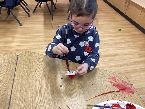 A school age child painting an egg carton poppy