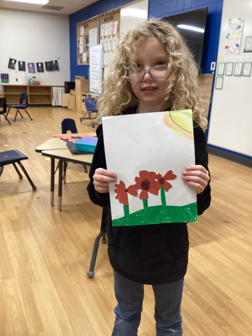 A school age child holding a photo of her poppy picture