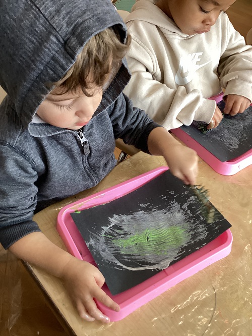 A child incorporating natural items into their artwork.