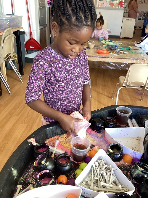 A preschool child engaged in sensory play at the tuff tray