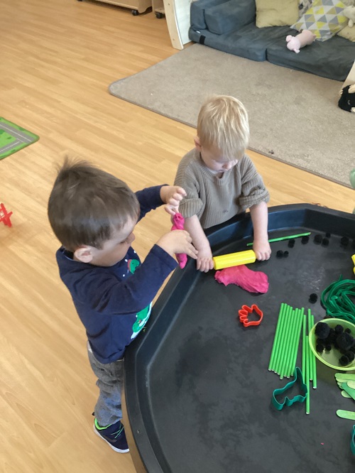2 toddler using playdough on a tuff tray