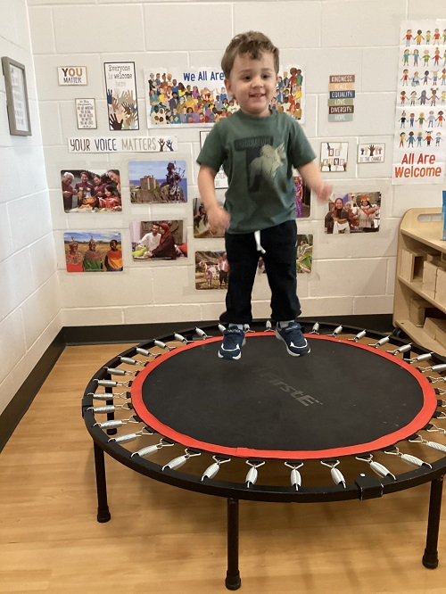 A preschool child jumping on an indoor trampoline