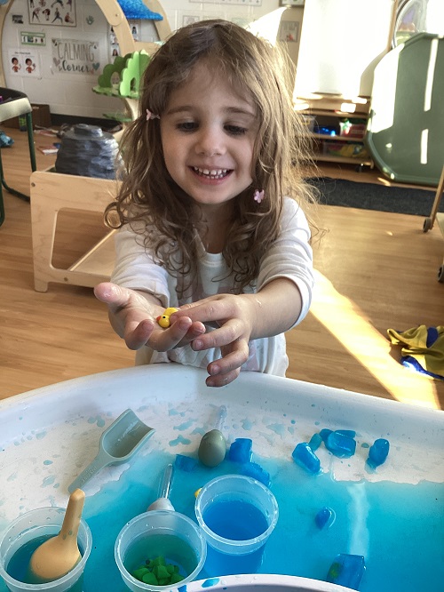 A preschool child holding a little duck with a big smile