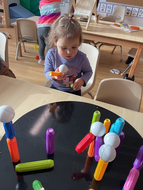 child at table with magnetic balls and connectors