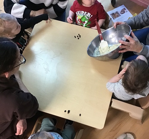 Infants and educators sitting at a table making a cake