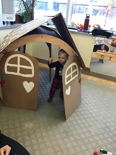 A child standing inside a big gingerbread house