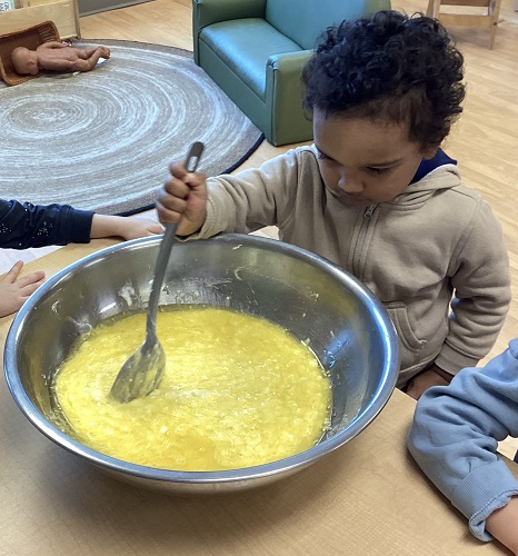 A child stirring a big bowl of muffing batter