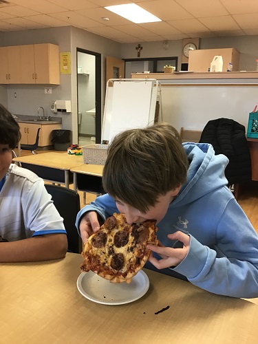 A school aged child eating the pizza he made