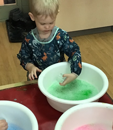 A child exploring with colourful water