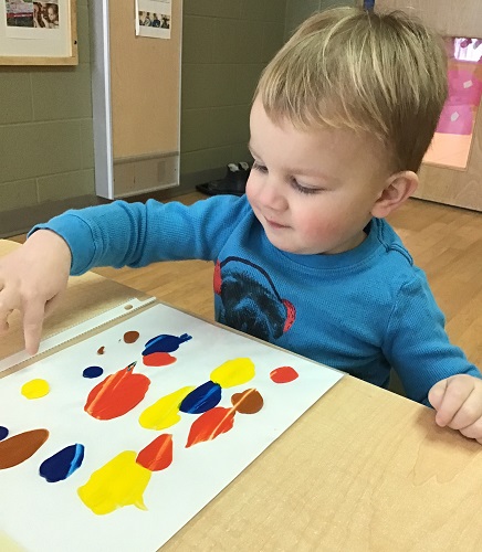 A child exploring with colourful paints