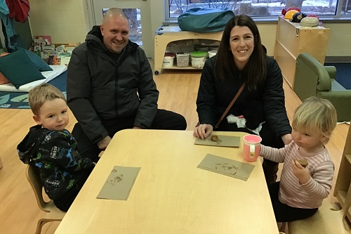 Tow children sitting with parents eating muffins together